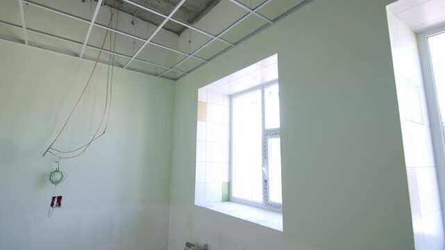 Light green walls enclose spacious facility room during interior rebuilding. Exposed electrical cables indicate active construction stage