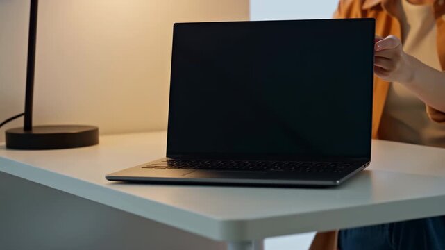 Woman opening a laptop computer on a desk at home