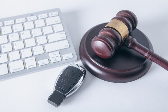 wooden judge gavel and car key on laptop computer, top view