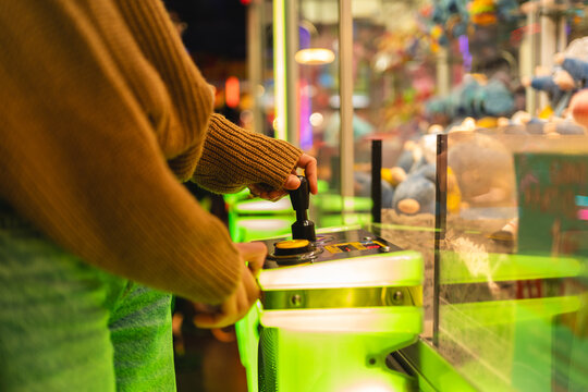 Person enjoying leisure and entertainment, controlling a joystick at an arcade claw machine