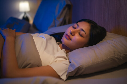 Beautiful asian woman lying in the bed at night. Young woman sleeping well in comfortable cozy fresh bed on soft pillow linen. Health and rest concept.