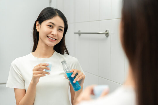 Young asian woman with mouthwash for the health of teeth in restroom. Take care and good dental health fresh breath with mouthwash.