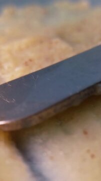 Spreading brown cream evenly with metal tool applicator. Close up of natural elasticity and smooth cosmetic texture.