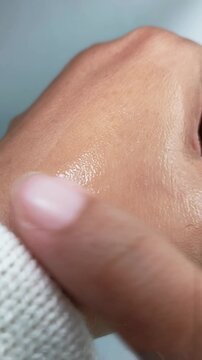 Applying clear cream for moist skin onto back of hand. Close up of beauty skincare cosmetic routine on gray background.
