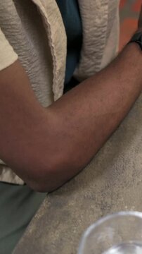 Vertical video: Placing right arm on table, man fitting black cuff and checking watch, copy space