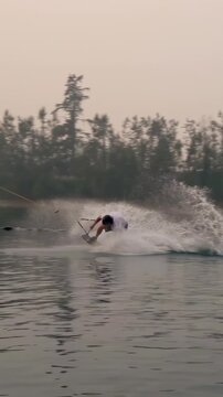 Vertical video: Cable pulling rider jumping ramp rotating riding lake with vest, board copy space