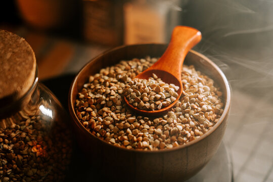 Organic green buckwheat grains in a wooden bowl with spoon at home