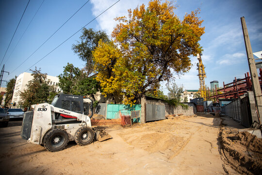 Compact white loader working on a dirt ground at a city construction project. Almaty, Kazakhstan - September 30, 2024