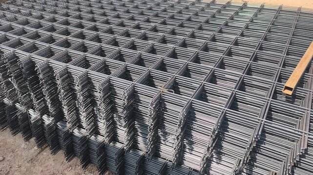 Steel BRC wire mesh laid on a construction site. Used for workers prepare the reinforcement for a concrete floor slab. This mesh ensures structural integrity and durability.