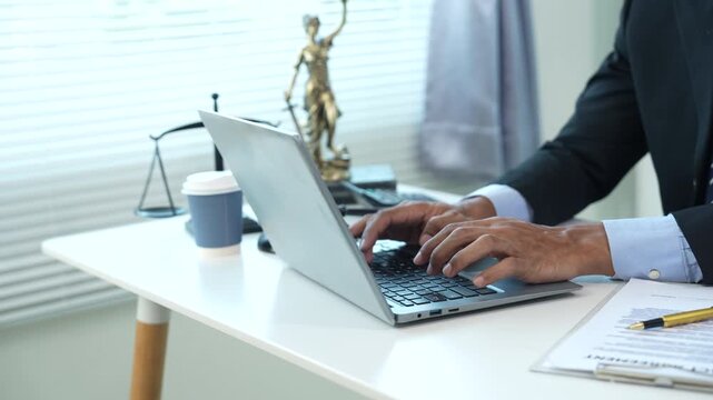 A legal professional works on a laptop beside justice symbols and documents, representing legal consultation, contract review, compliance, digital law services, and business governance.