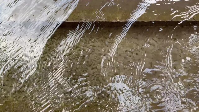 The close-up of ripples from the clear spring reveals tiny pieces of algae at the bottom of the pool.