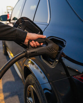 Close up of hand charging a black electric car with EV charger