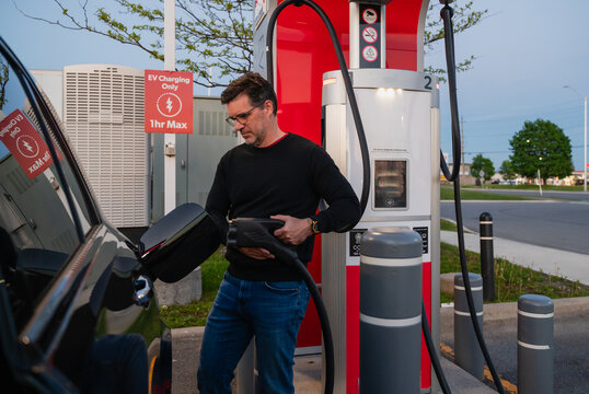 Man charges his black electric car at a public station