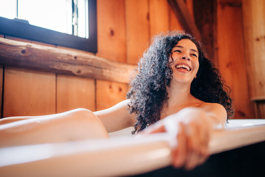 Smiling woman relaxing in a bathtub in a rustic cabin