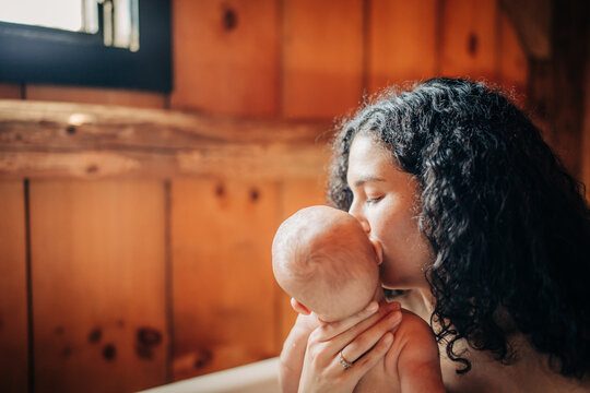 Mother kissing newborn baby displaying love and affection