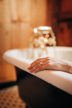 Hand with diamond engagement ring relaxing in bathtub