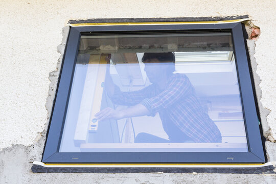 Man with water level at window during house renovation