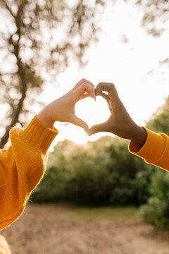Couple making heart shape with hands at forest