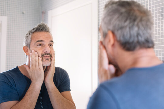 Mature man looking in bathroom mirror