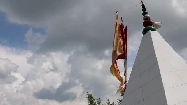 Raw video footage of a religious temple flag with Lord Hanuman image and Jai Shree Ram text waving in strong wind under cloudy sky in Uttarakhand India.