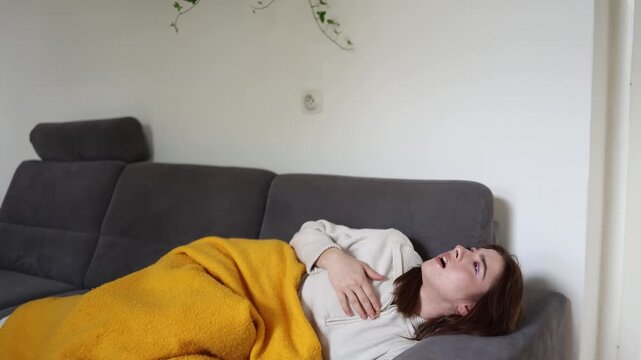 Young woman lying on sofa feeling severely ill with suspected hantavirus infection experiencing weakness fever breathing discomfort and flu like symptoms during recovery at home