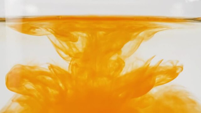 Macro slow motion of orange liquid formula dissolving in clear water, cosmetic antioxidant vitamin C serum texture for skincare commercial.