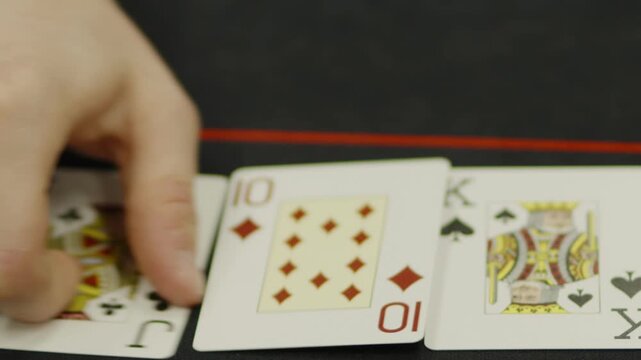  A close-up shot of a hand turning over playing cards