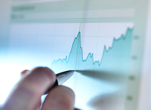 Hand of a stock broker analysing line graph on computer screen