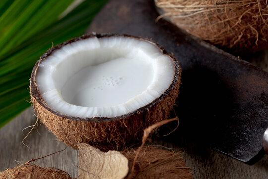 Half coconut with coconut milk and sickle, close up