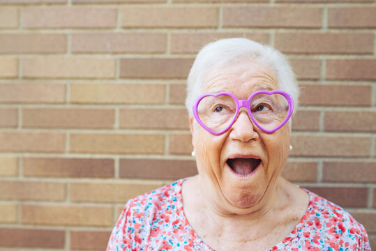Portrait of senior woman wearing heart-shaped glasses pulling funny faces
