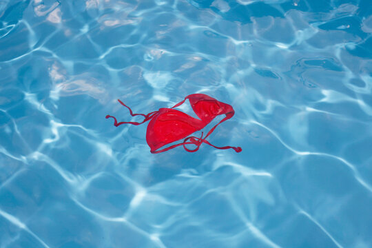 Germany, Red bikini top floating in swimming pool