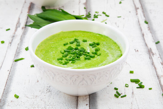 Bowl of ramson soup garnished with chives and cream