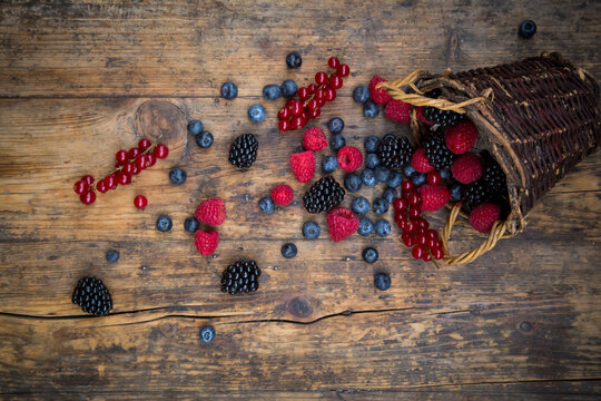 Wickerbasket of various berries on wood