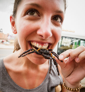 Cambodia, Young woman eating fried tarantula spiders