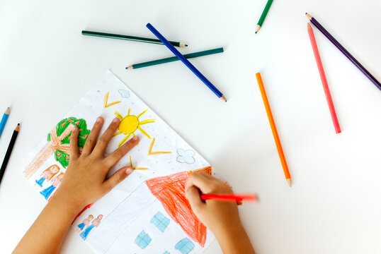 Hands of little girl painting with coloured pencils