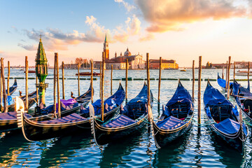 row of parked venetian gondola boats in Grand canal of Venice. Beautiful sunset or sunrise landscape with gondolas in blue water of Venice. © Yaroslav