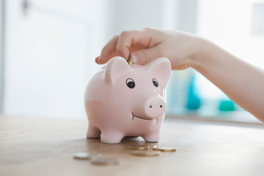 Little boy putting coin into piggy bank, close-up