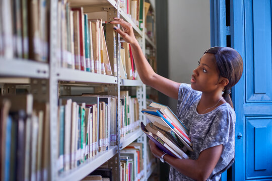 Young woman checking the books at the bookshelves at National library, Maputo, Mocambique