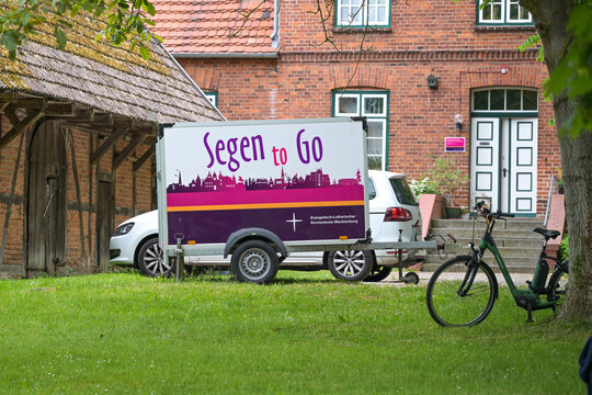 Schlagsdorf, Germany, May 31, 2026: Trailer with the lettering Segen to go (meaning blessing to go) parking in front of an old parsonage, religious initiative by the Protestant Church, selected focus