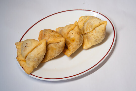 Veg Samosa Indian Food served fresh on a white red-rimmed platter against a white background