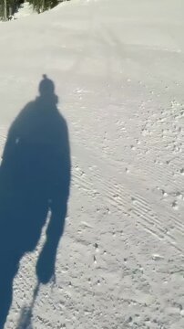 Vertical video: Passing boarder, skier filming groomed tracks with jacket, poles, copy space