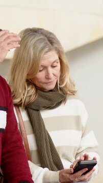Vertical video: Glancing after pal lifting cup, woman in striped sweater scrolling phone at station
