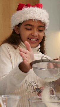 Vertical video: Sifting kid Santa hat tapping sifter as mom holding sieve at home, whisking to bake