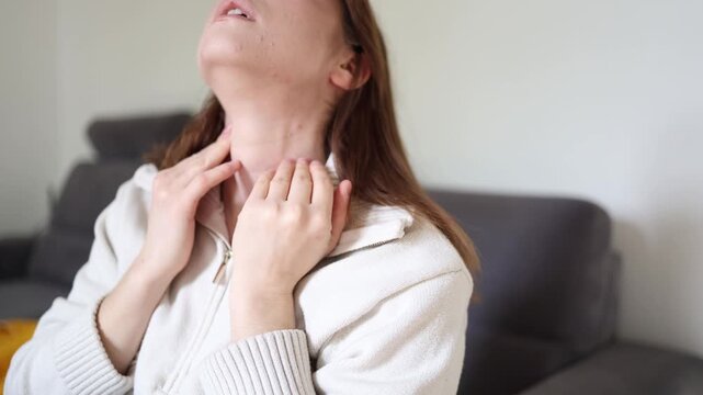 Close up of worried young woman checking thyroid gland and neck area at home while monitoring possible hormonal imbalance and endocrine health problems