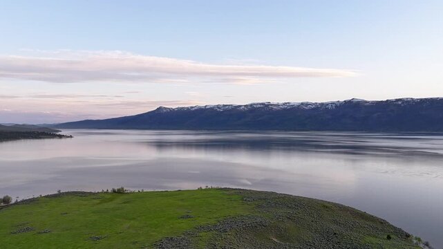 Gentle dawn light bathes lake and mountains