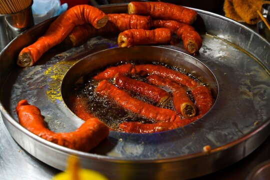 Traditional deep fried pig intestines cooking in boiling oil pan at Temple Street Night Market street food stall under evening lights in Hong Kong