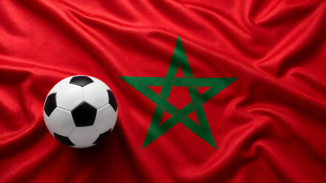A classic black and white soccer ball resting on the red and green flag of Morocco, symbolizing the country's passion for football and sports culture.