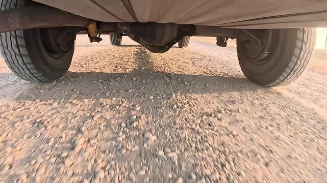 Low angle captures truck wheels rolling over gravel
