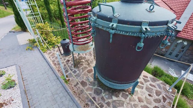 Tihany, Hungary - May 19, 2026: Close-up view of a traditional distillation apparatus with copper cooling coil and metal tank displayed outdoors as part of local cultural and industrial heritage in th