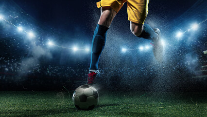 Soccer player foot controlling ball under stadium lights with flying turf. Concept of sportswear advertising, match banners, soccer academy promotion, and team campaign visuals. © master1305
